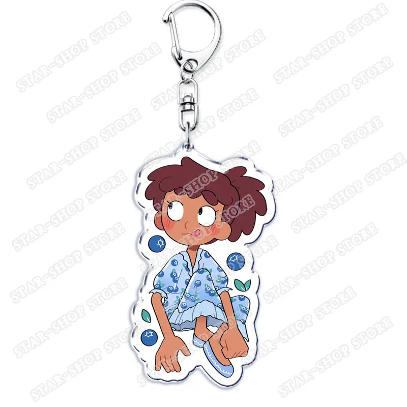 Clear acrylic Amphibia anime keychain featuring a cartoon character with brown hair and rosy cheeks wearing a light blue patterned dress with blueberry motifs.