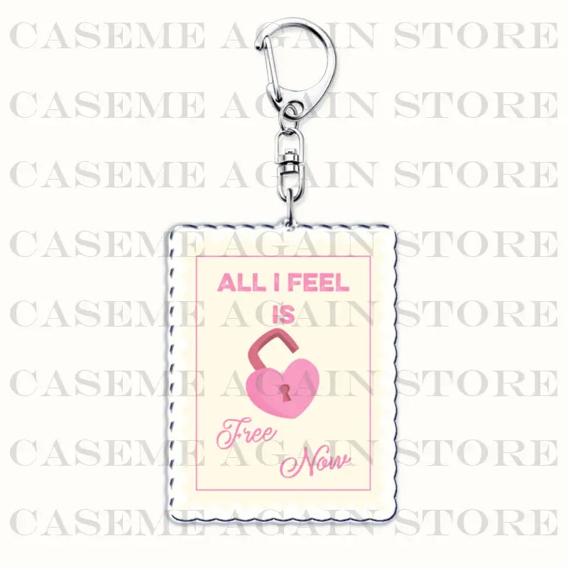 A pink heart-shaped acrylic lock keychain with the text all i feel is free now printed in matching pink on a cream-colored background with a stitched border and a silver metal clasp for anime fan gift use.