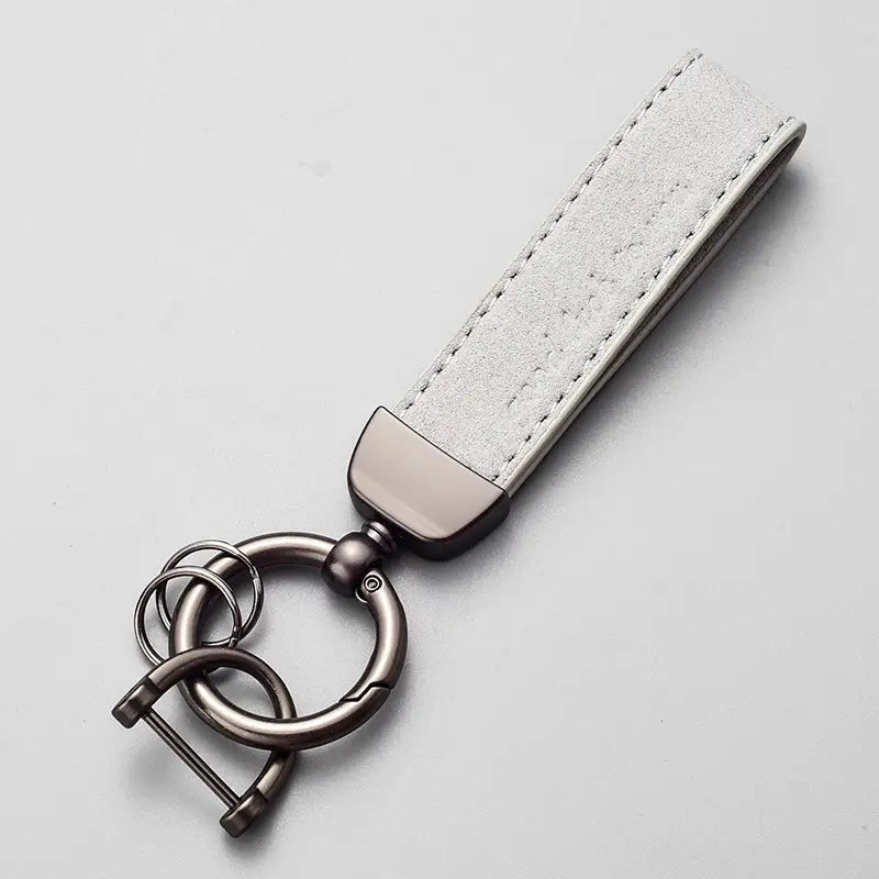 A sleek silver-gray suede leather car keychain with a matte-finished metal clasp and multiple rings for organizing keys.