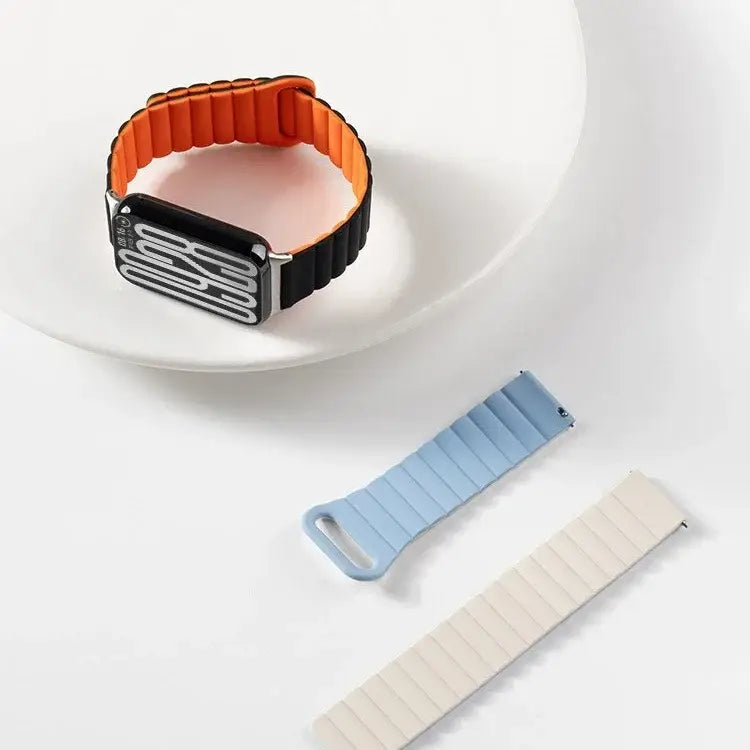 Orange-schwarzes, segmentiertes Silikon-Magnetarmband für die Xiaomi Redmi Watch, dargestellt mit passendem Apple-Watch-Zifferblatt.