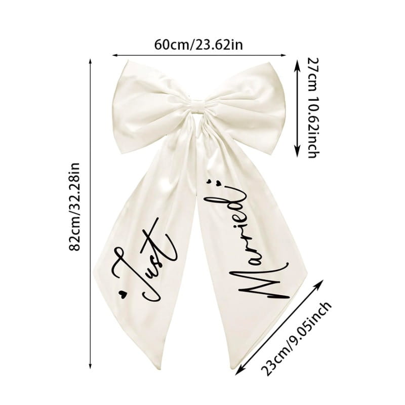Un nœud de voiture « just married » en satin crème, fraîchement noué, avec une écriture noire cursive sur ses deux pans, pour la décoration de mariage.