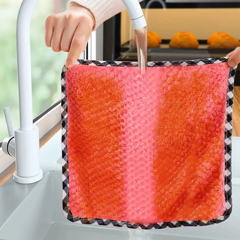Un essuie-tout en microfibre rayé rose et orange vif, avec une bordure à carreaux noir et blanc, fabriqué dans un tissu moelleux très absorbant.