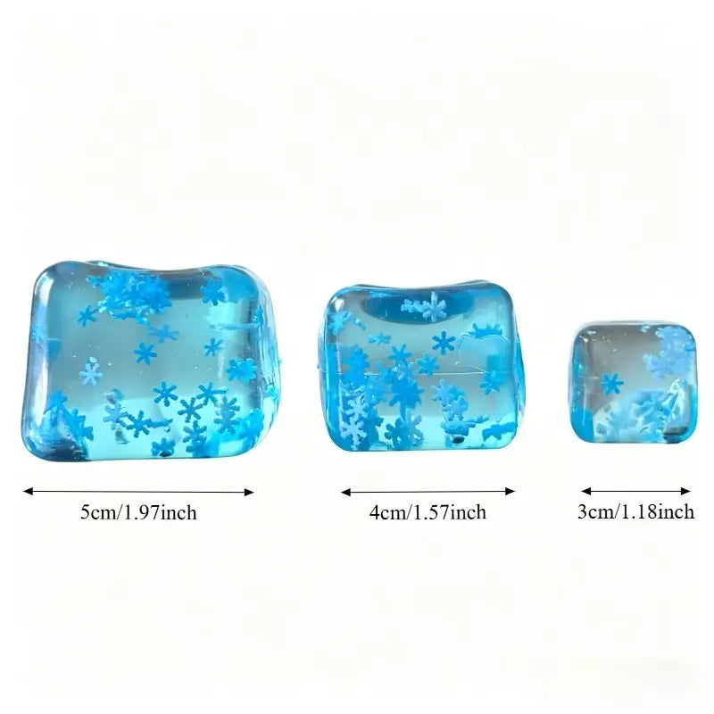 three translucent blue resin squishy snowflake ice cubes with embedded snowflake designs in varying sizes from 5cm to 3cm slow rising sensory fidget toy.