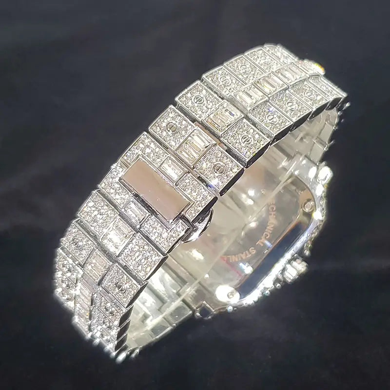A luxurious silver-toned iced out diamond square watch for men featuring an intricate pavé design with baguette-cut and round diamonds accented by a central rectangular pinkish-gold tone plaque.
