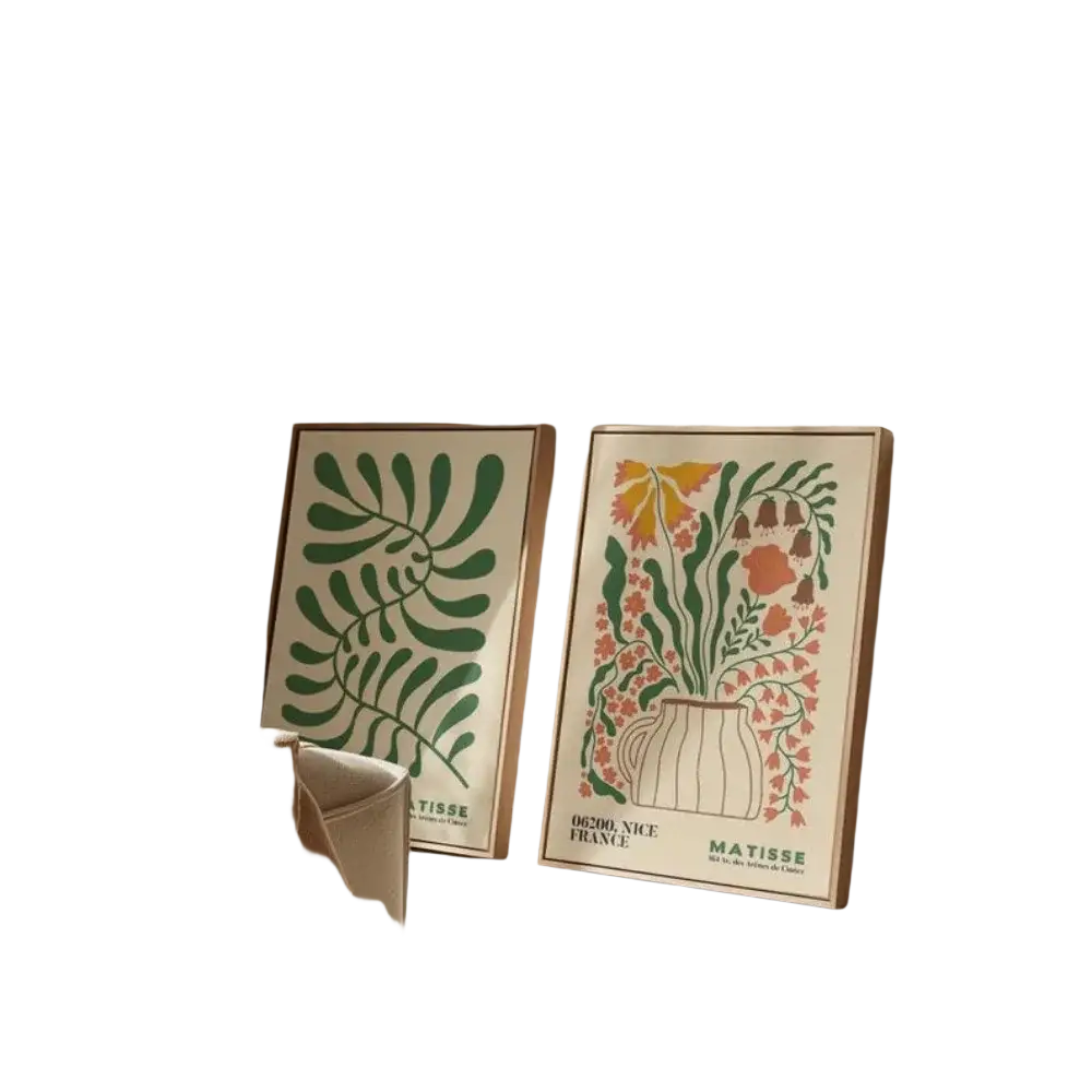 Two framed matisse-style posters with green foliage and colorful flowers leaning against a wall for wall decor