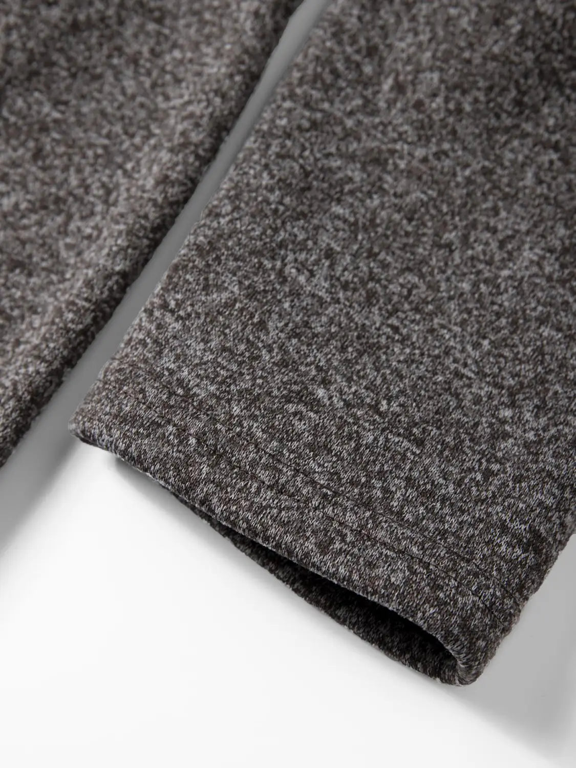 a close-up of the cuff on a dark gray fleece lined knit hooded jacket highlighting its textured knit material for men