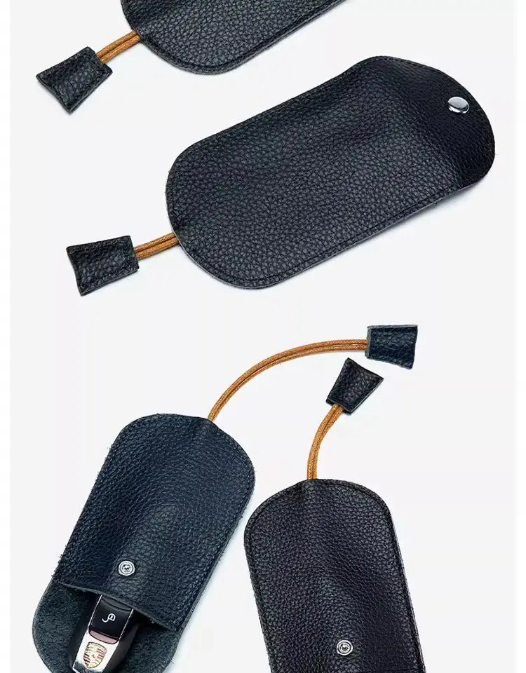 Schwarzes genarbtes Leder-Schlüsseletui mit Taschenhalterfunktion, mit beigefarbener Kordel und schwarzen Stoffenden.
