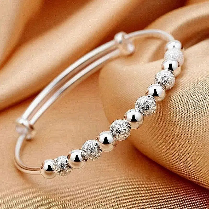 Silver beaded bangle bracelet for women featuring an adjustable design with alternating polished and textured spherical silver beads.