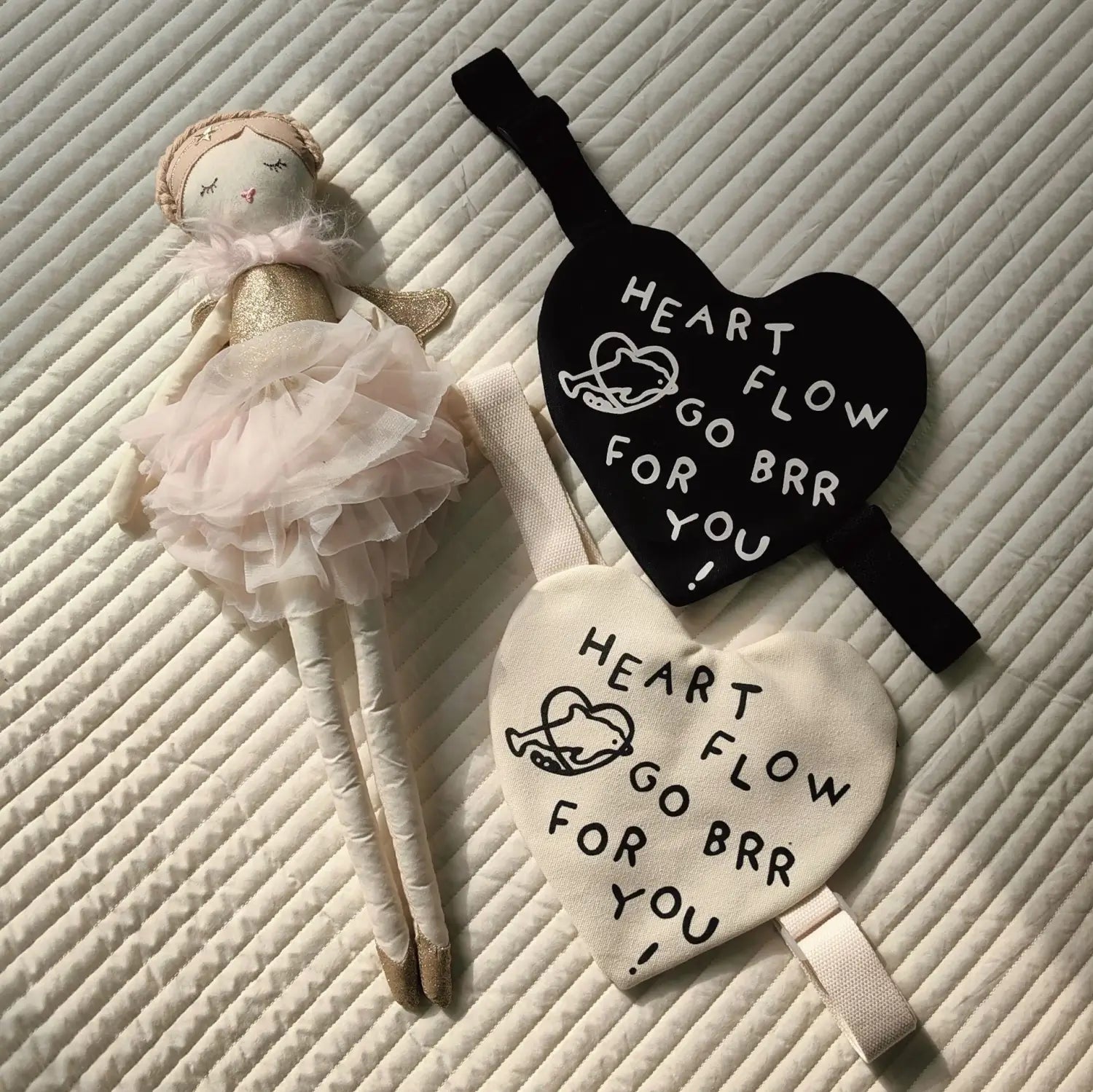Eine schwarze und cremefarbene herzförmige Schlafmaske mit weiß besticktem Text „heart flow go brr for you“ und einer kleinen Wal-Illustration für die koreanische Kinder-Umhängetasche mit Herz-Crossbody.