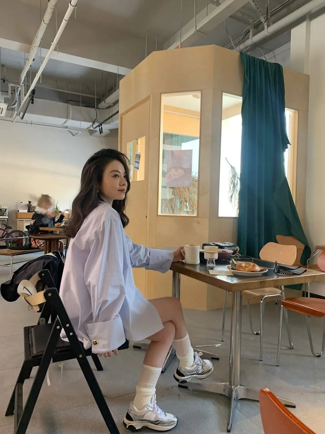 white oversized button-up shirt with rolled sleeves and gold-tone buttons shown from the front in a light blue oversized button-up shirt product listing.