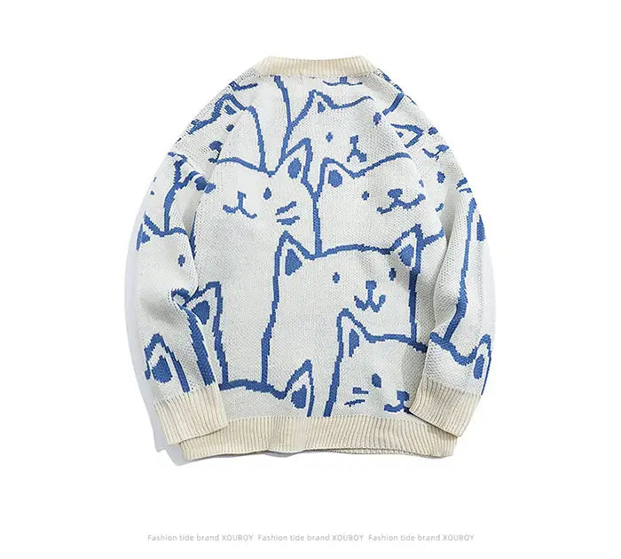 Pull ample en maille de couleur crème, présentant un motif ludique de chats de dessin aux contours bleus, inspiré du style Harajuku.