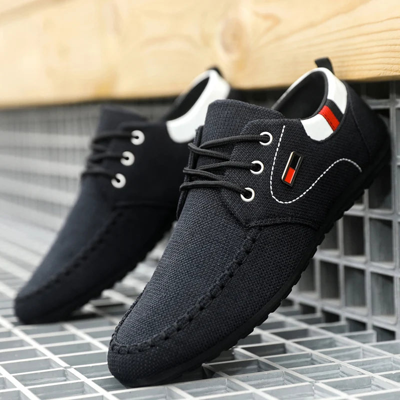Men’s casual canvas sneakers lightweight daily footwear in black with white stitching red and black logo patch and white accents around the collar.
