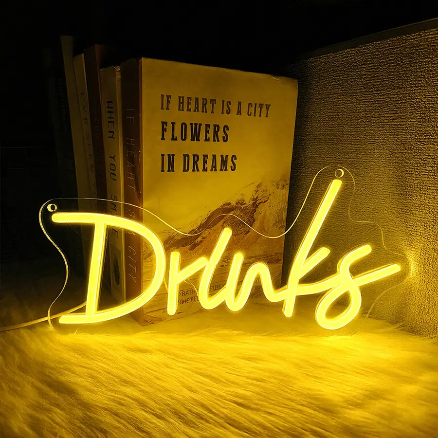 une enseigne au néon jaune lumineuse en écriture cursive, épelant « drinks », conçue comme décoration murale à LED