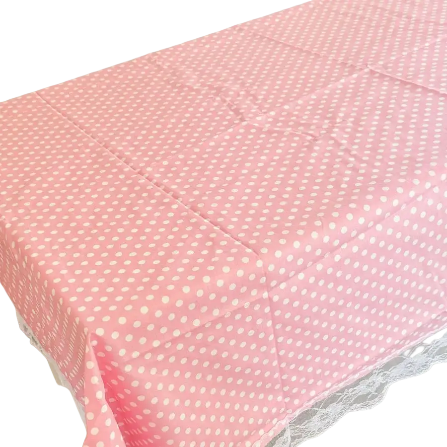 Se muestra una mantelería rosa con lunares con ribete de encaje blanco desde un ángulo cenital.