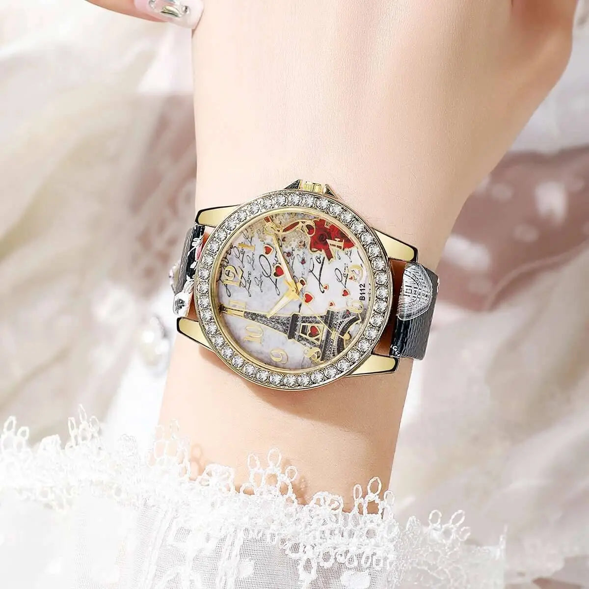 A gold-toned eiffel tower floral quartz women watch with a sparkling diamond bezel and an intricate parisian-themed dial featuring the eiffel tower and red heart motifs.