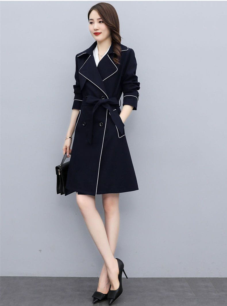 Women double breasted trench coat in black with white contrast stitching and a belted waist.