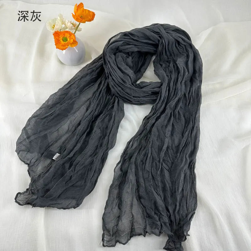 Écharpe en coton et lin plissé gris foncé, à la texture froissée légère, souple et fluide.