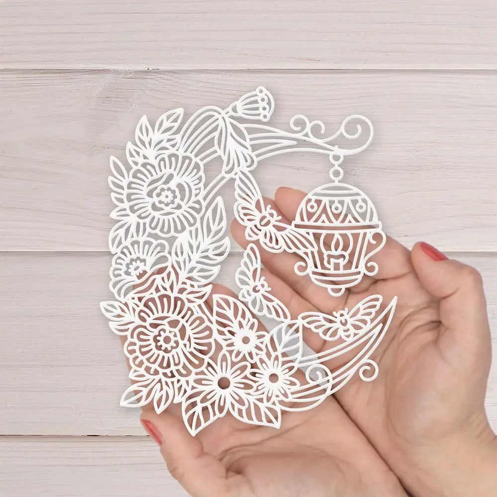 A delicate white metal cutting die featuring an ornate lantern hanging from a crescent moon with intricate floral and butterfly designs for Chinese New Year crafts.