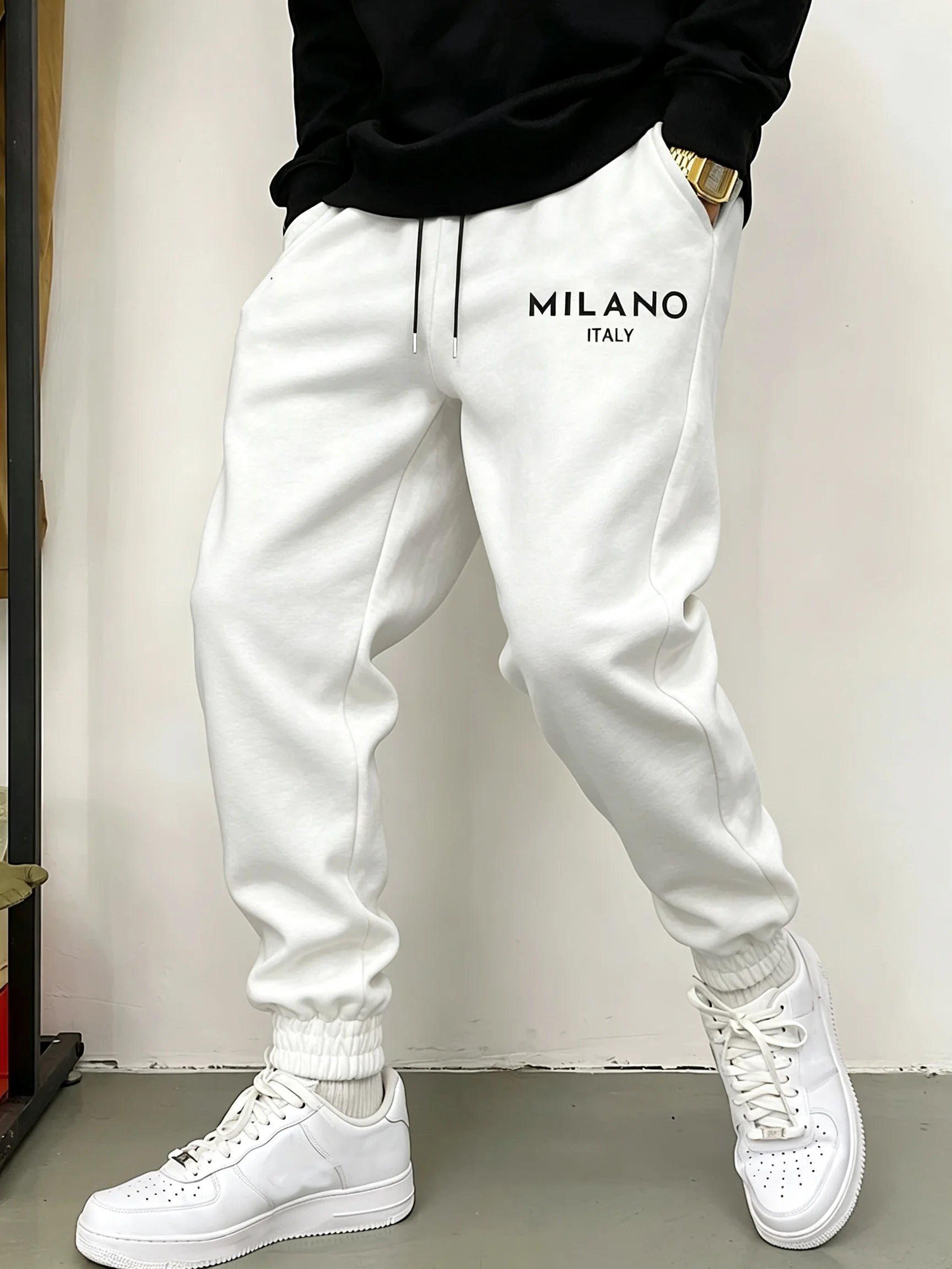 Weiße Fleece-Jogginghosen für Herren mit in Schwarz auf der linken Oberschenkelseite besticktem Milano, Italien, mit Kordelzugbund und elastischen Bündchen.