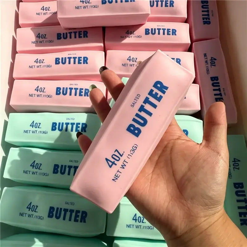 Rosa gesalzener Butterriegel als ASMR-Sensory-Squishy-Spielzeug in einer rechteckigen Umverpackung mit blauem Schriftzug und 4 oz Nettogewicht