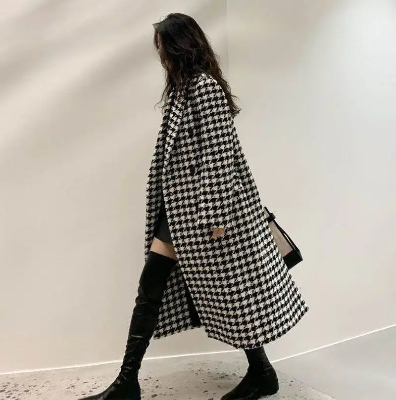 A houndstooth wool double breasted coat featuring a long black and white pattern with a classic tweed texture.