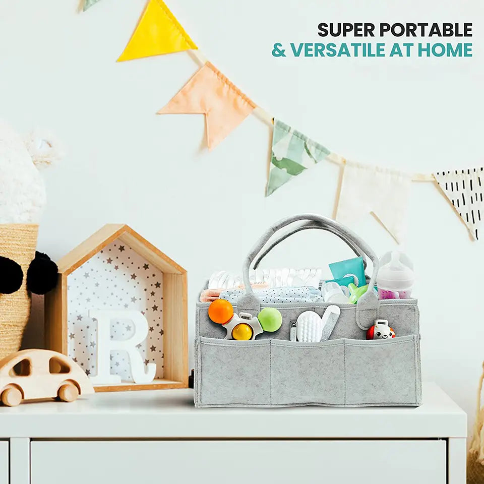 Grand sac organisateur en feutre gris pour couches, avec plusieurs compartiments et des anses souples pour les essentiels de bébé.