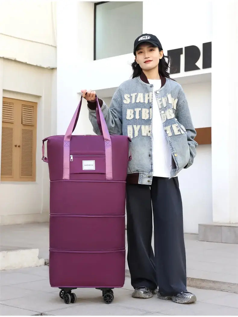 Un sac duffel roulant pliable violet à grande capacité, avec des poignées roses et des roues noires, conçu pour un usage de grand sac à dos et de voyage.