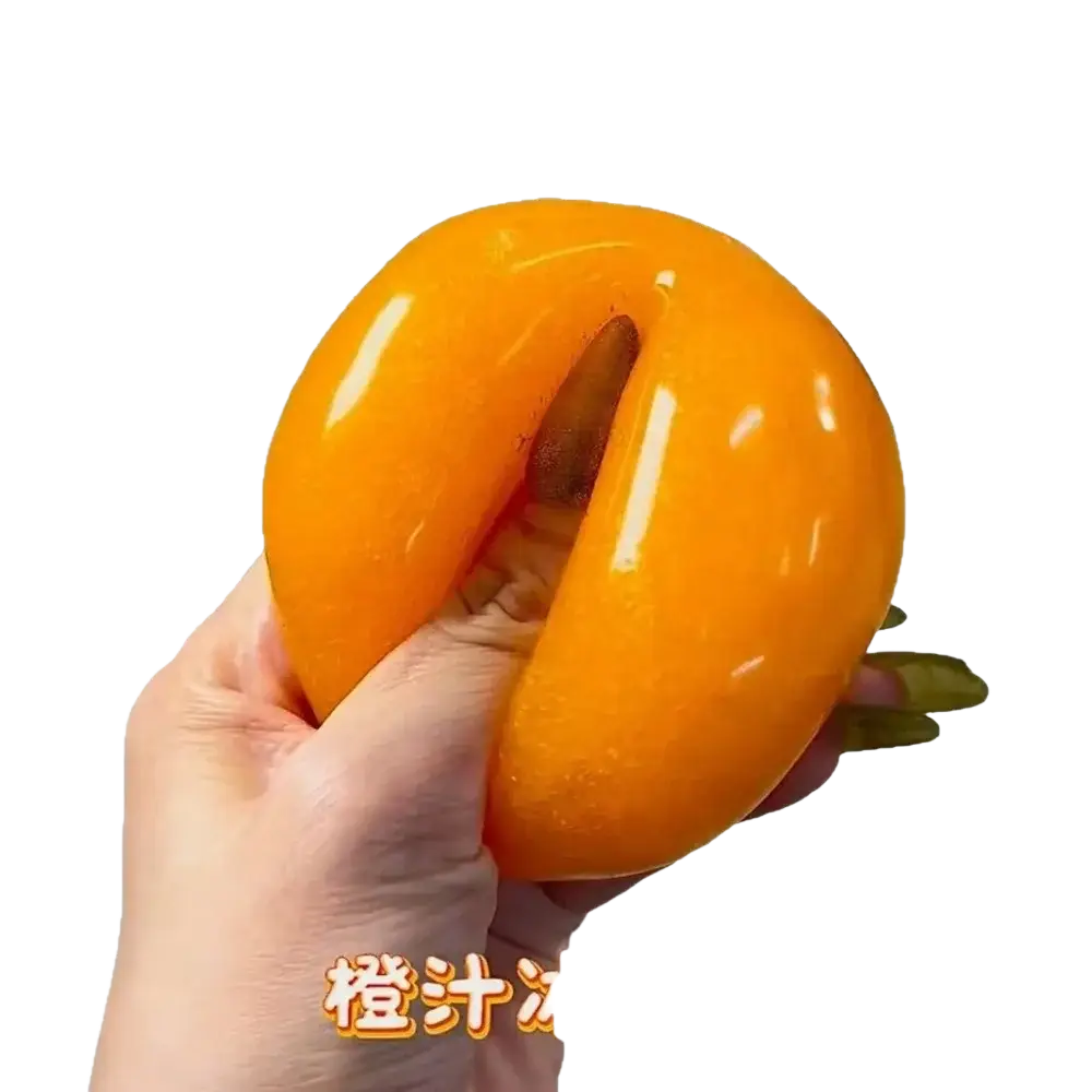 Handmade orange slushy squishy toy shaped like a glossy persimmon with a central slit and green stem visible from front