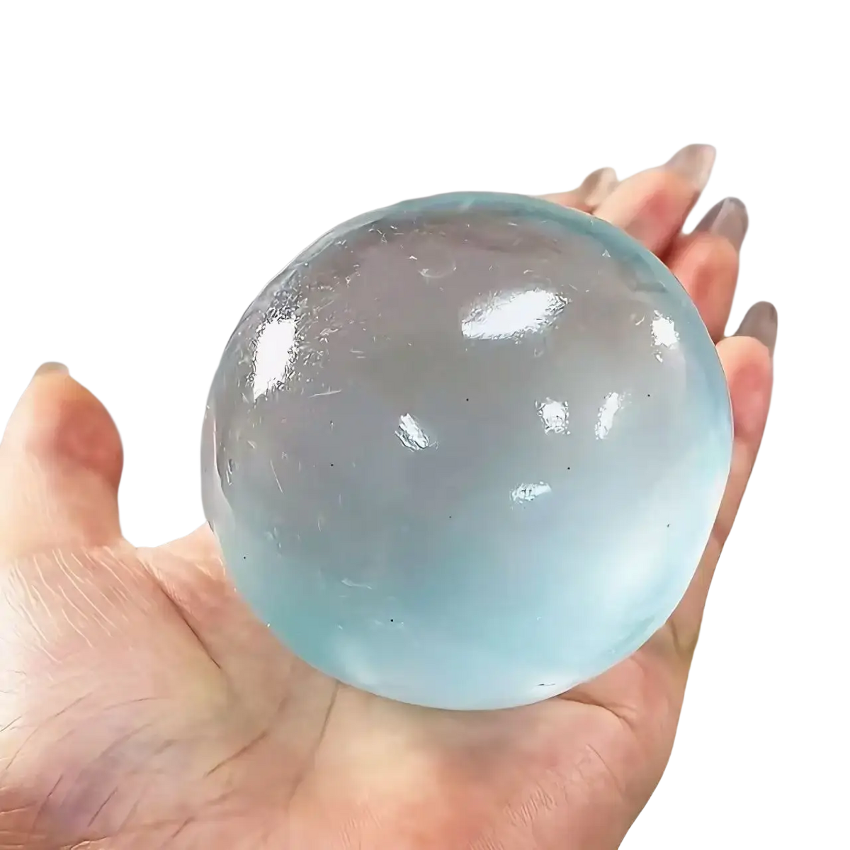 A translucent light blue gel ball stress toy filled with coconut oil held in a hand for squeezing and stress relief