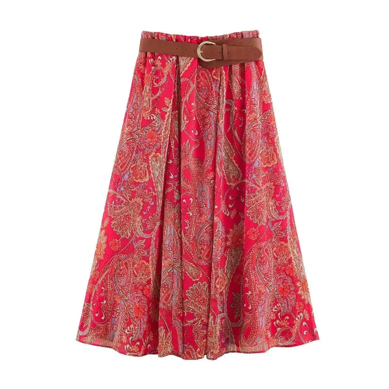A vibrant red paisley midi skirt set featuring an intricate pattern in gold brown and muted purple with a tan leather belt cinching the waist.