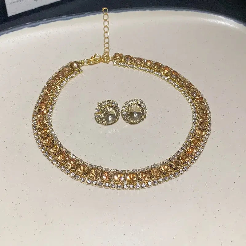 Gold-toned crystal necklace and earring set featuring a choker necklace adorned with rows of amber and clear rhinestones in an intricate metal design for pink ab wedding jewelry.