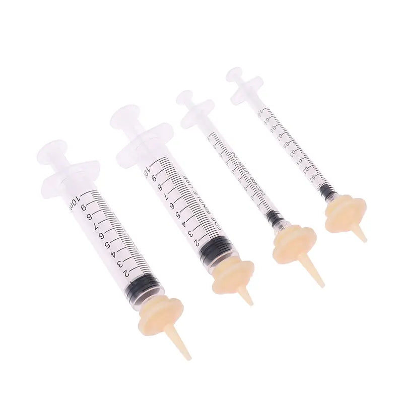 Clear plastic pet oral syringes with black measurement markings and beige caps featuring silicone nipples for feeding.