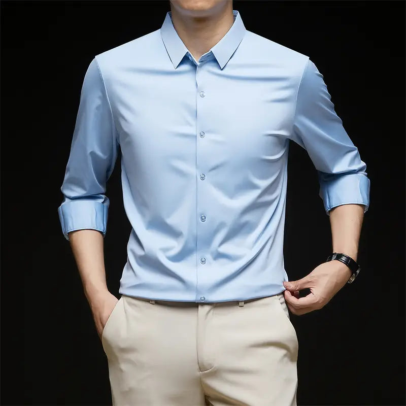 Camisa de vestir para hombre sin arrugas color azul claro, con mangas largas, cuello clásico y parte delantera abotonada, adecuada para uso formal y de negocios.