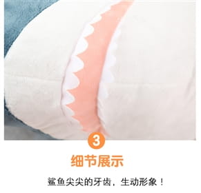 A plush blue shark stuffed animal pillow featuring a soft white body with pink scalloped-edged teeth.