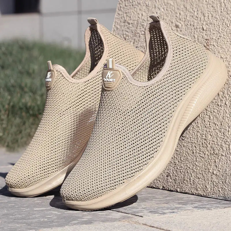 Baskets décontractées pour hommes à enfiler en mesh beige, avec semelle en caoutchouc souple et étiquette de logo de marque, conçues pour favoriser la respirabilité et le confort.