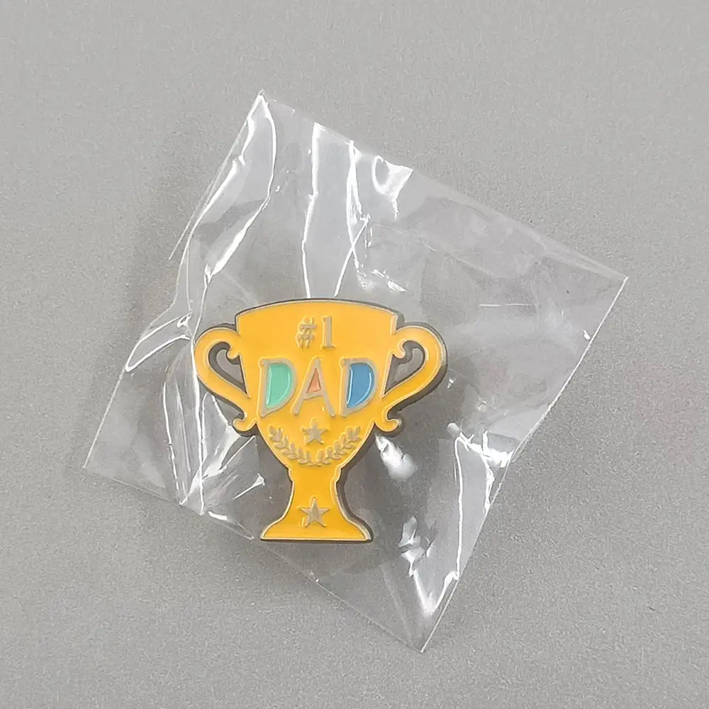 Broche en émail jaune en forme de trophée avec des lettres « #1 Dad » colorées et des accents en forme d’étoiles dans un design de broche dorée.