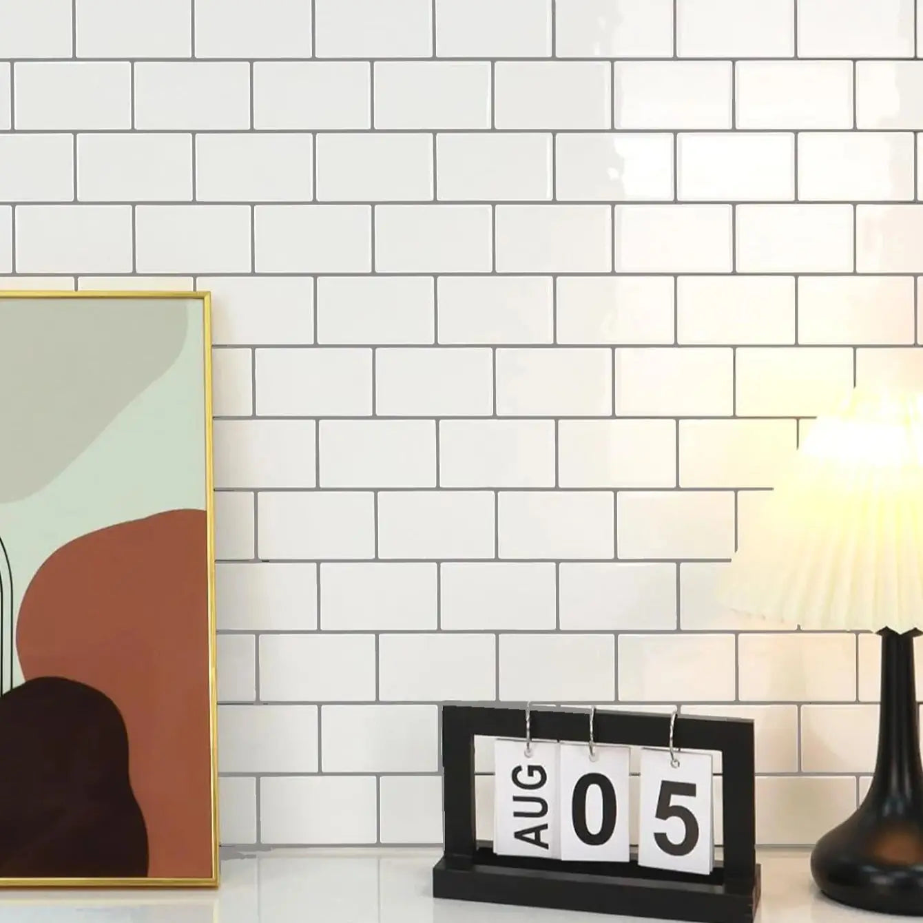 black wooden-framed flip calendar displaying aug 05 with white numbered panels alongside glossy white peel and stick backsplash tile subway suitable for direct contact with fresh paint surfaces