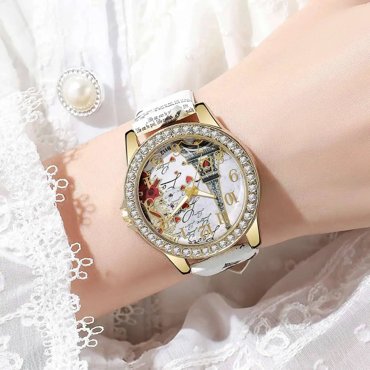 A gold-toned Eiffel Tower floral quartz women watch with a sparkling diamond bezel and an intricate design of the Eiffel Tower and playing cards on its white face.