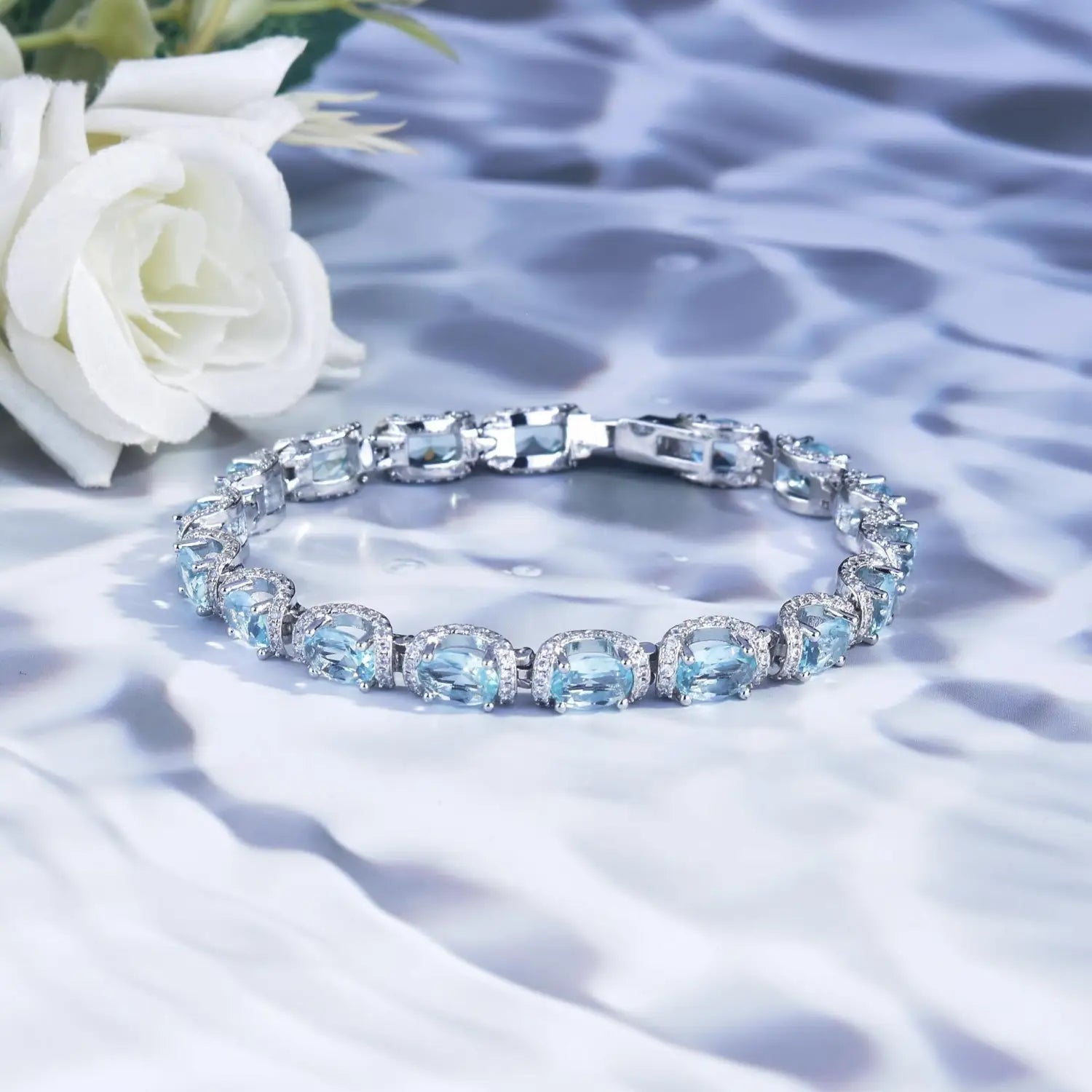 A delicate silver bracelet from the aquamarine crystal bridal jewelry set featuring oval-cut sky blue topaz stones and sparkling accent diamonds.
