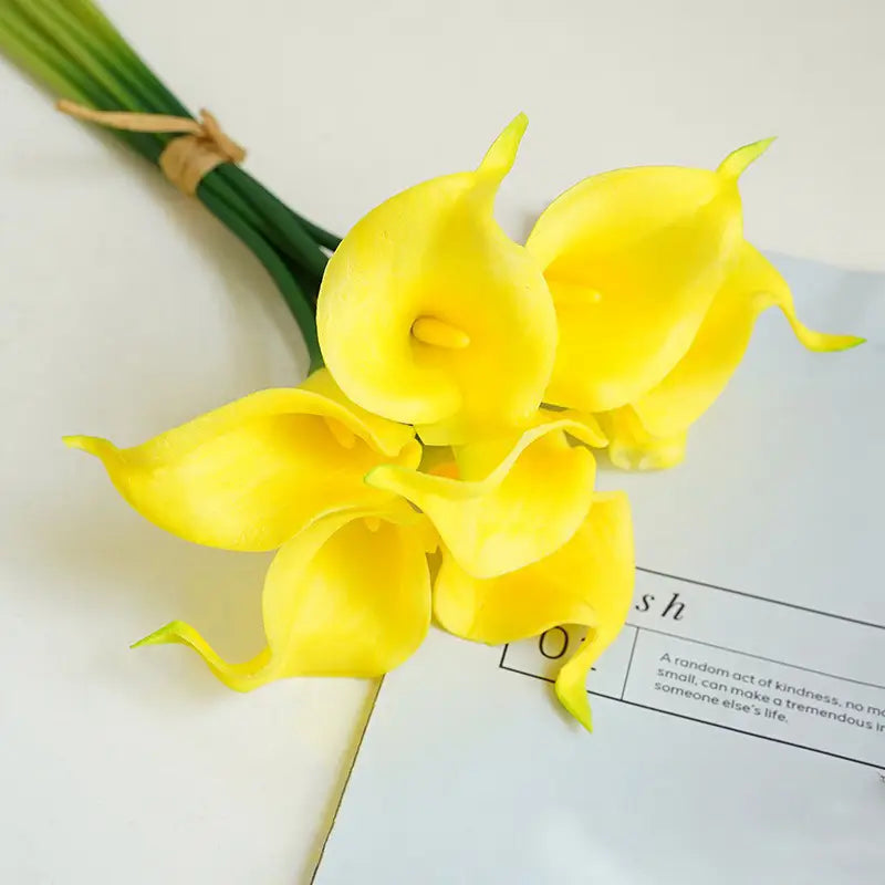a vibrant yellow artificial calla lily flower bouquet with green stems tied together by rustic twine for home decor.