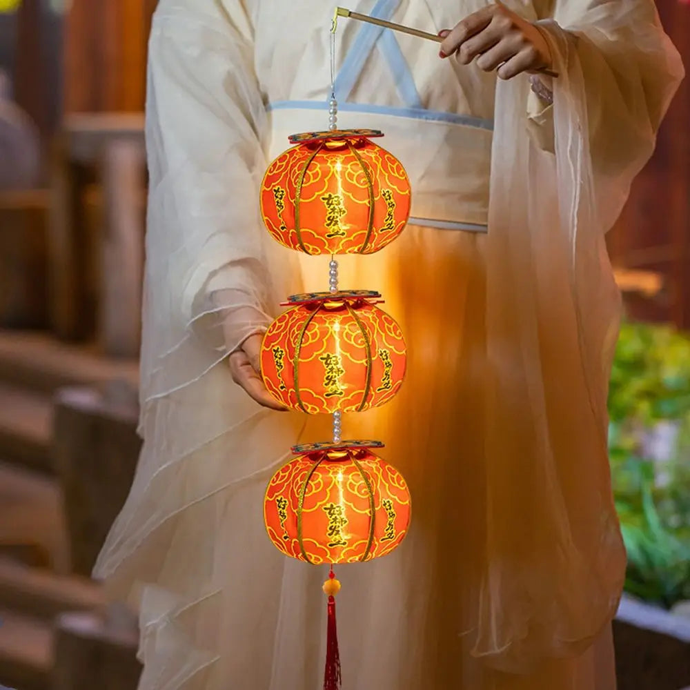 Lanterne de kaki à trois niveaux, avec des motifs floraux et calligraphiques dorés, illuminée de l’intérieur par une lumière LED chaude, conçue pour la décoration du Nouvel An chinois.