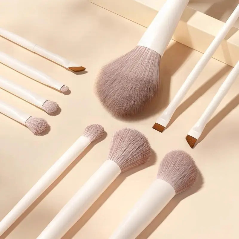 Ensemble de pinceaux de maquillage comprenant 12 pinceaux à manches blancs, avec des poils gris clair doux et des bagues en bois pour l’application cosmétique.