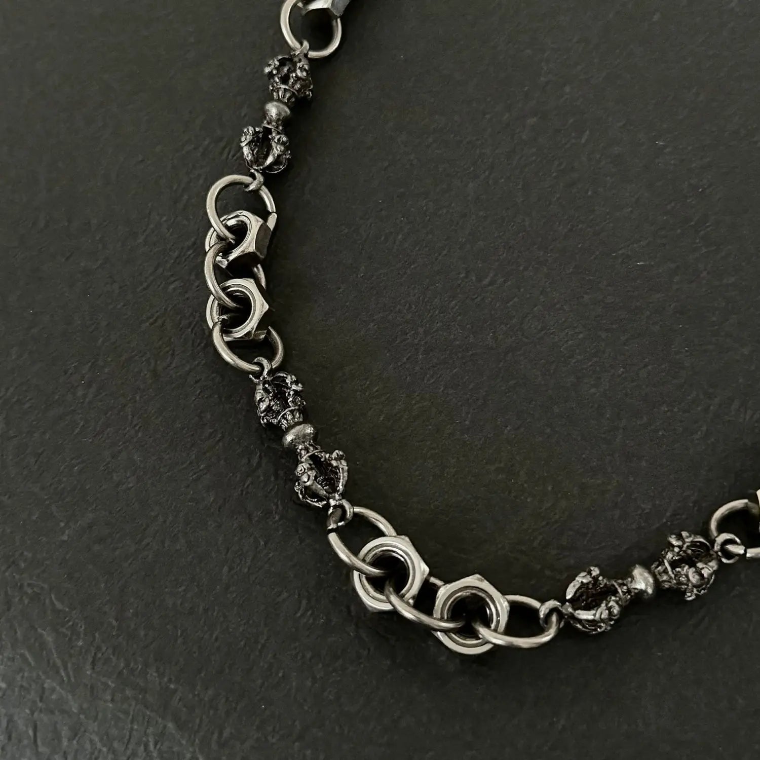 A dark textured metal men eagle punk trouser chain featuring intricate skull-shaped beads and heavy metal interlocking links for wallet accessory use.