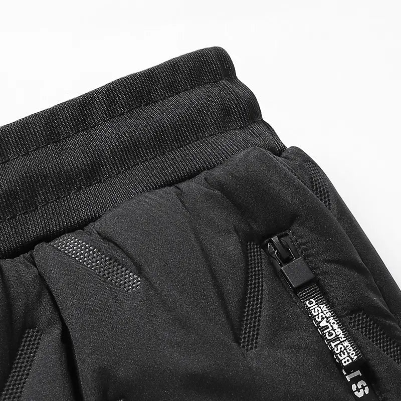 Black men fleece lined thermal sweatpants with a ribbed elastic waistband and mesh paneling on the side designed for waterproof winter use.