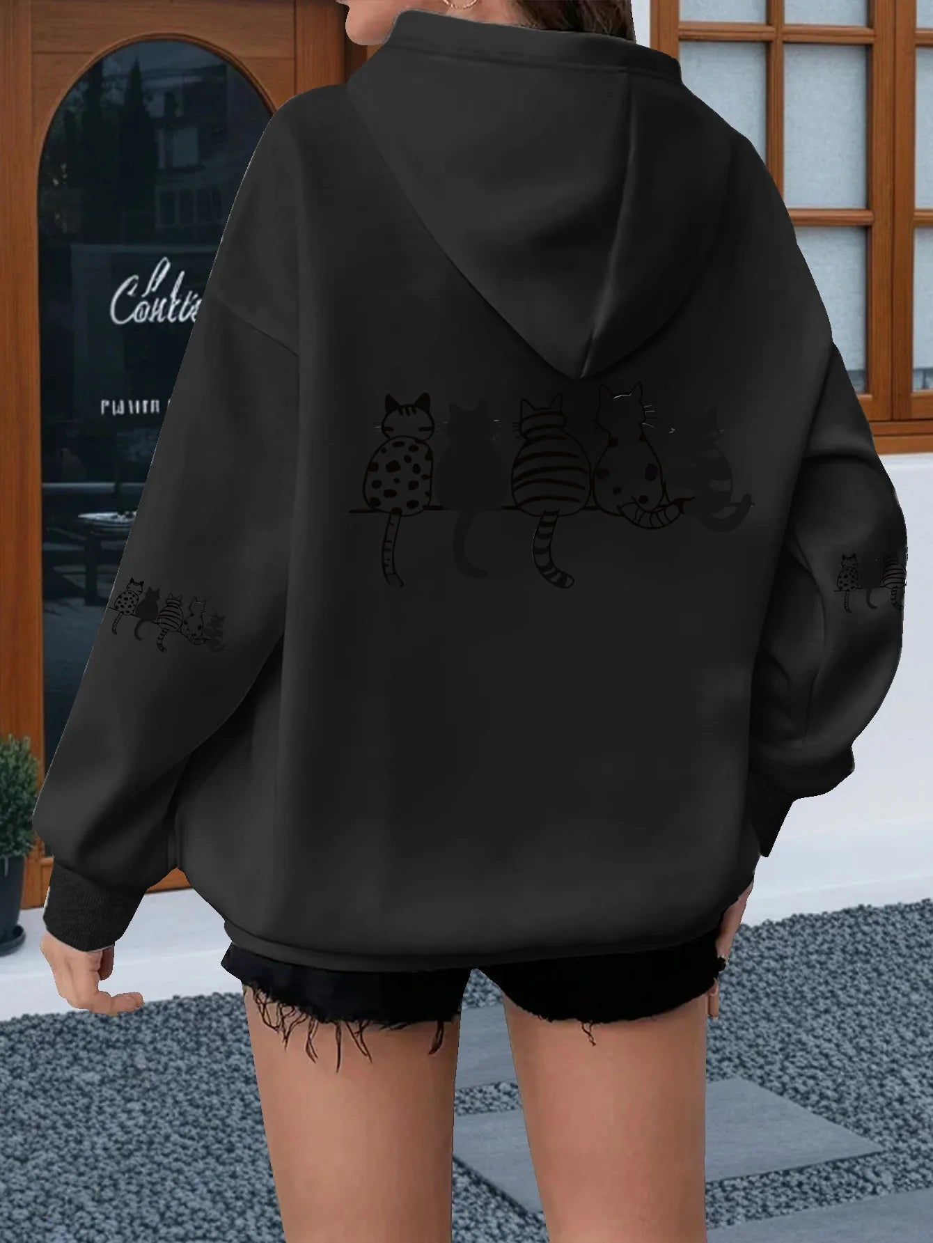 Le côté arrière du sweat à capuche décontracté pour femmes noir présente un motif de chat ludique imprimé en noir au dos et sur les manches.
