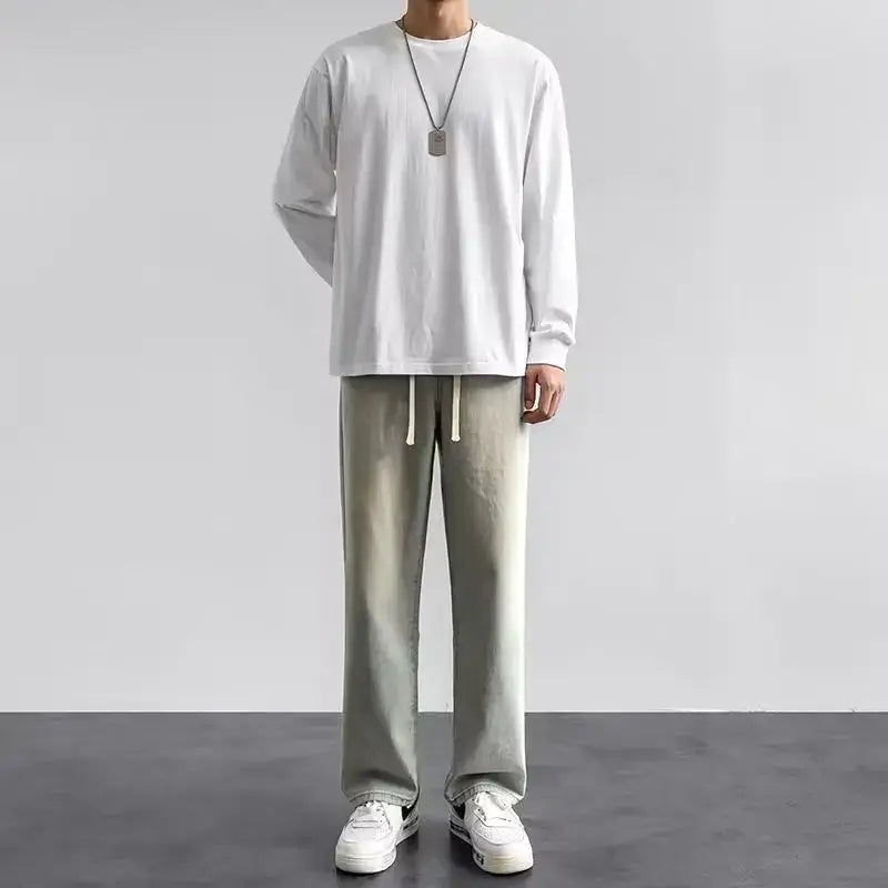 Le mannequin porte un pantalon de jogging droit gris clair avec des cordons blancs, assorti à des jeans en denim Y2K à jambes larges et ample pour hommes.