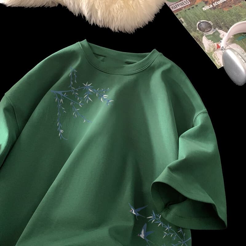 Camiseta de algodón oversize suave en color verde con delicados motivos de bambú bordado en azul y pájaros.