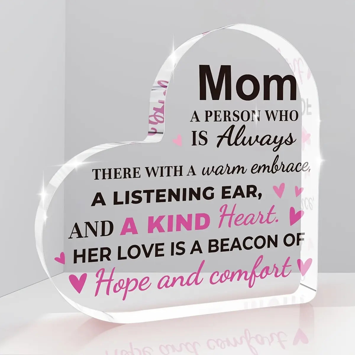 Clear heart-shaped acrylic plaque with black and pink text reading mom a person who is always there with a warm embrace as a mom acrylic heart keepsake gift.