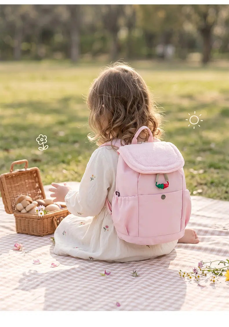 Leichter Fuzzy-Rucksack für Kinder in Pink aus plüschigem Material mit einem kleinen bestickten Erdbeerdetail auf der Vorderseite, geeignet für die Verwendung als Kindergartentagesrucksack.