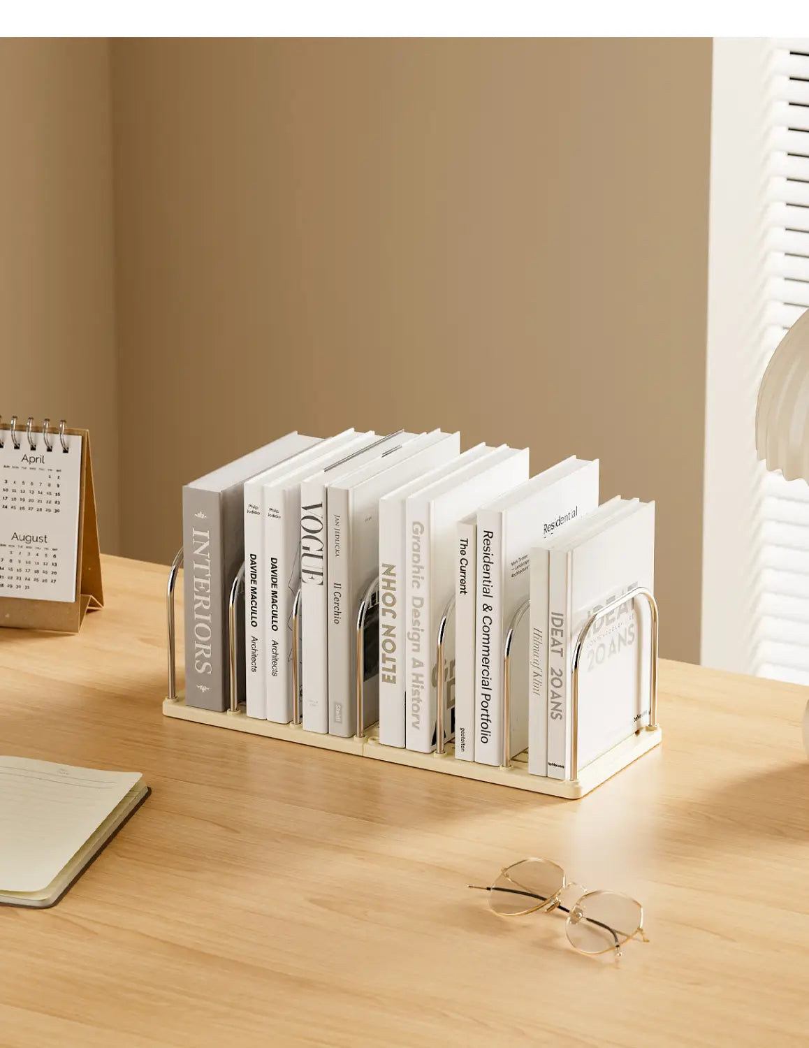 Organisateur de bureau minimaliste blanc pour livres, avec des arceaux métalliques élégants soutenant une rangée soignée de livres, et intégrant une horloge et des tiroirs.